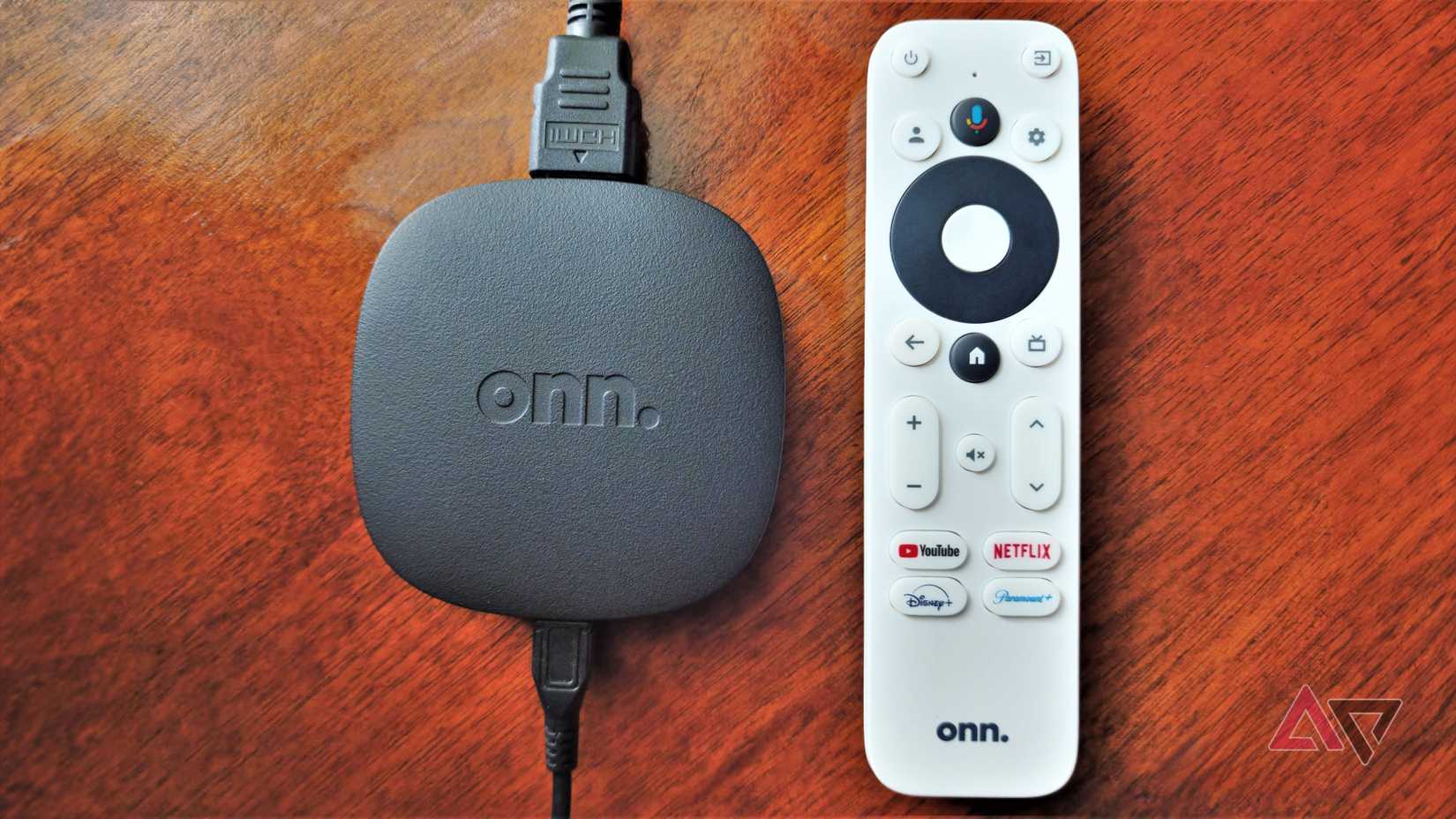 A caixa de streaming Onn em uma mesa de madeira ao lado do controle remoto.