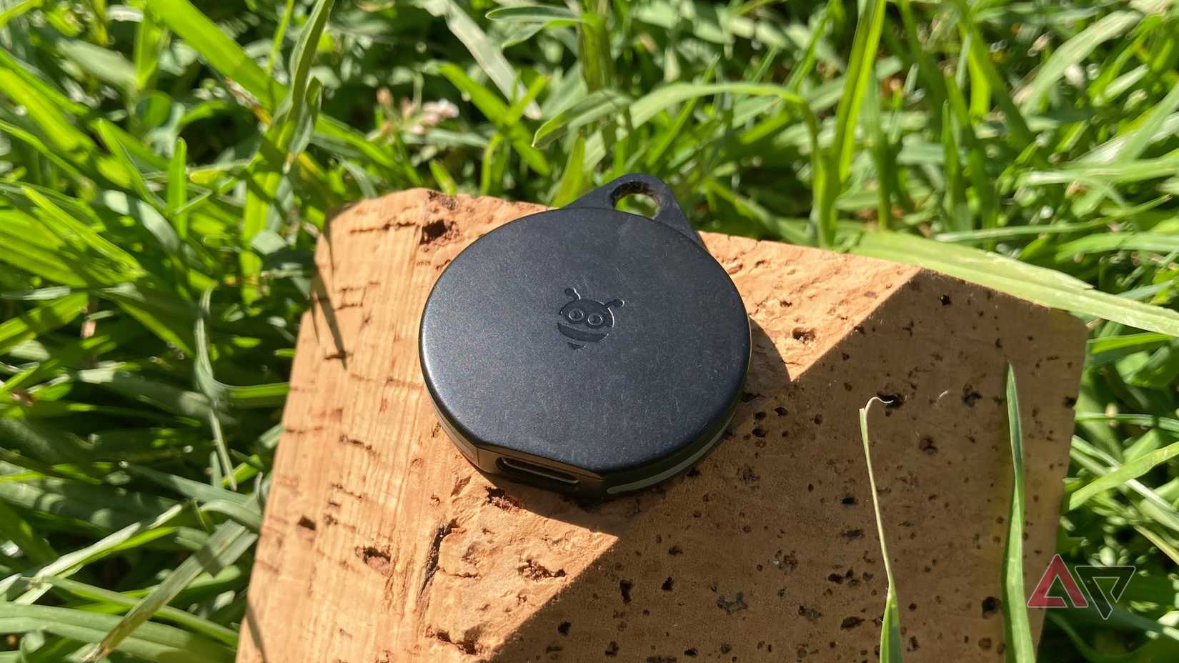 Il Pebblebee Clip per Android seduto sull'angolo di un mattone di sughero nell'erba