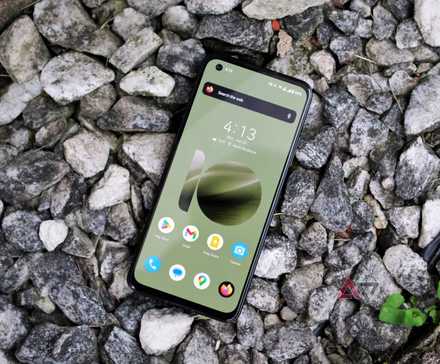 A smartphone with a green display rests on rocks.