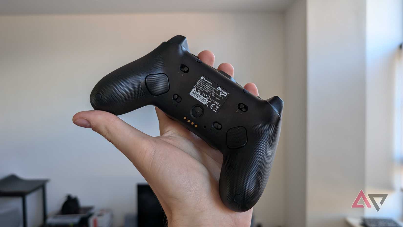 hand holding black gamesir controller showing back