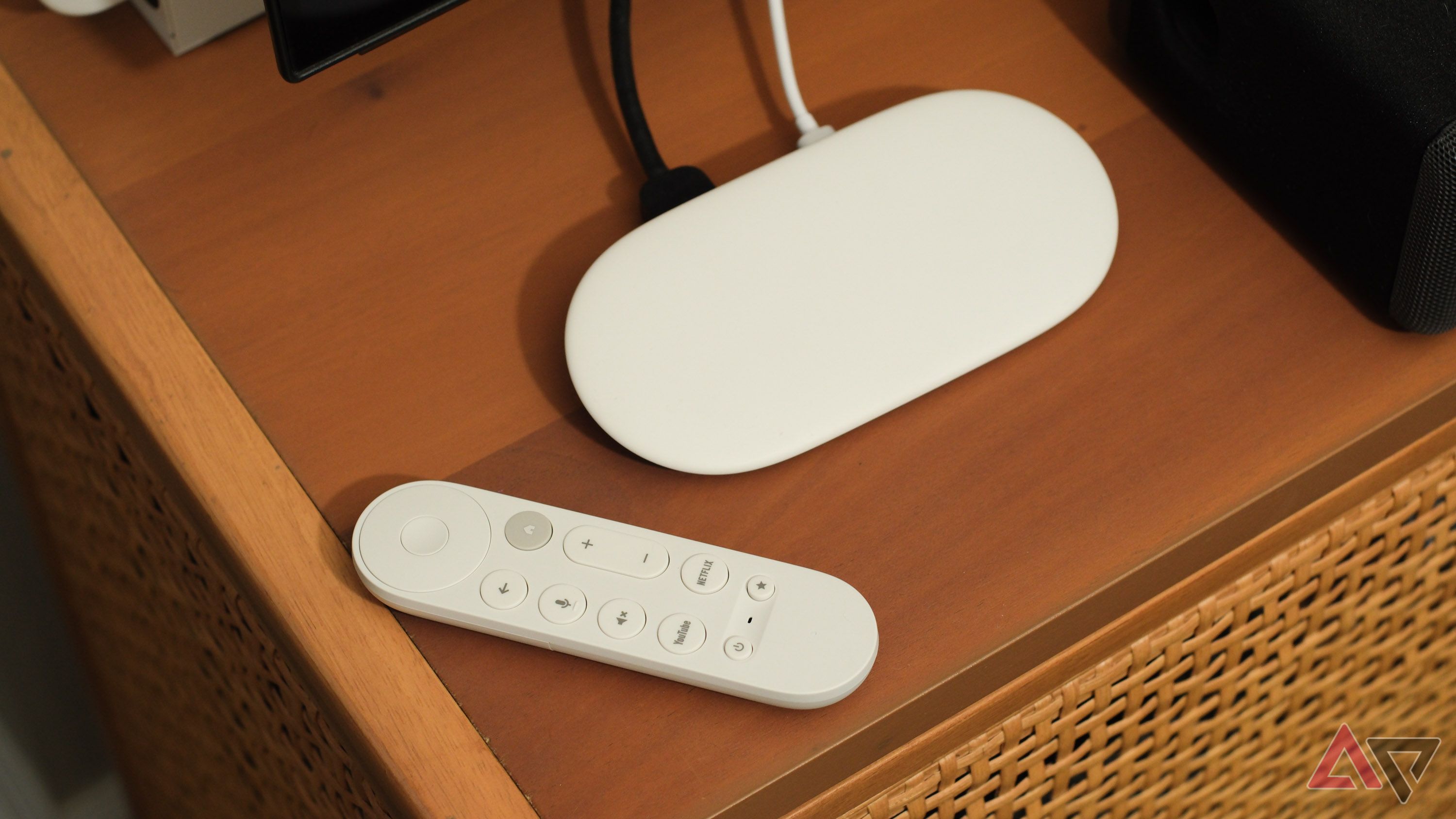 The Google TV Streamer with its remote on a TV stand.