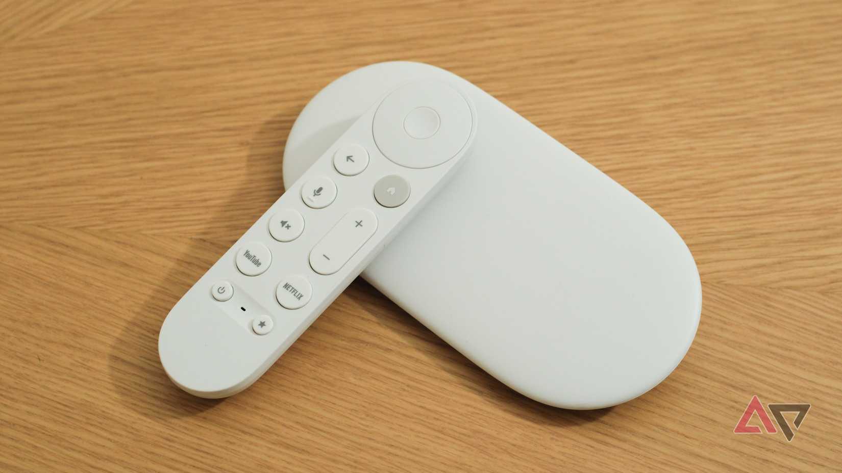 The Google TV Streamer with its remote leaning against it on a wooden surface.