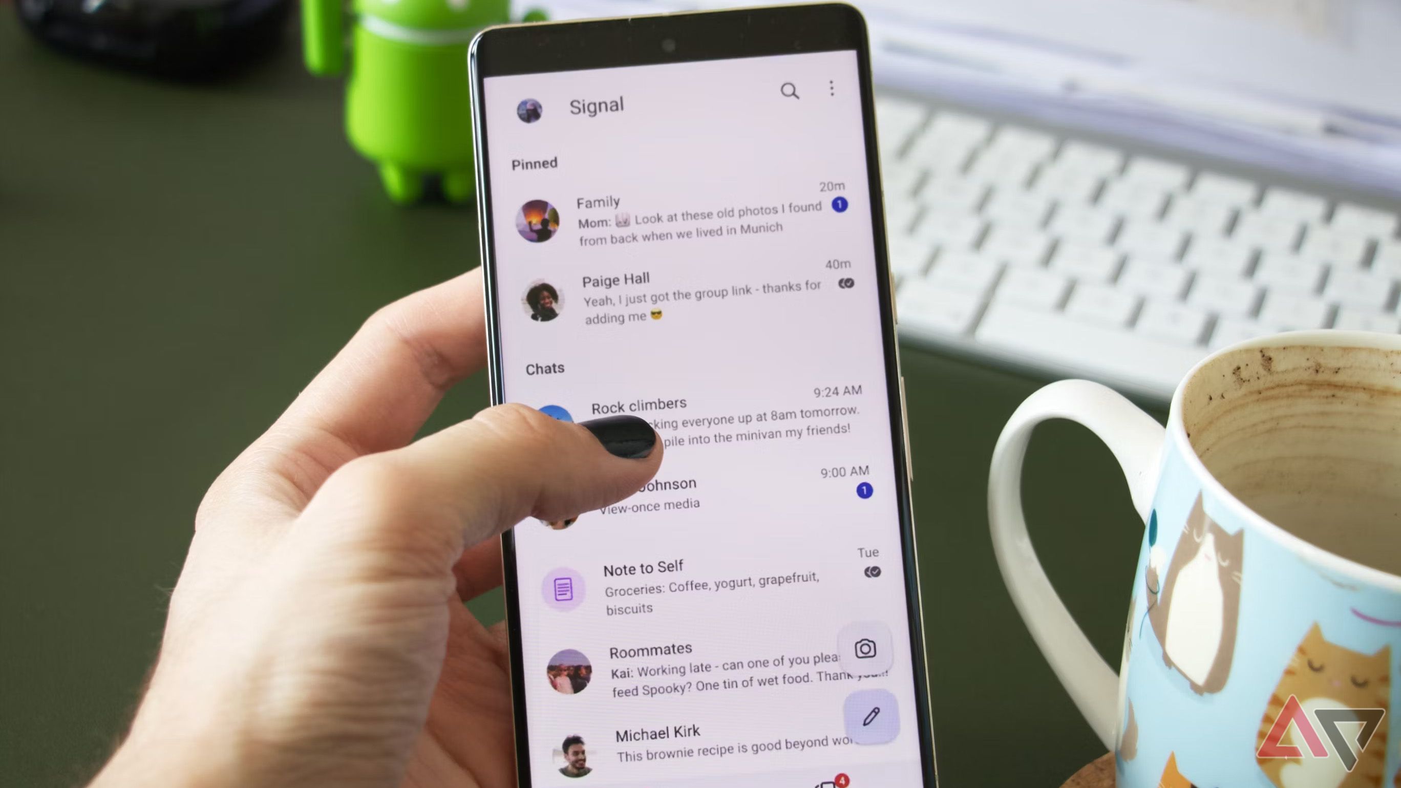 A person is holding a Google Pixel 7 Pro, interacting with the Signal chat overview