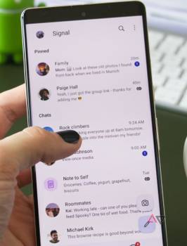 A person is holding a Google Pixel 7 Pro, interacting with the Signal chat overview
