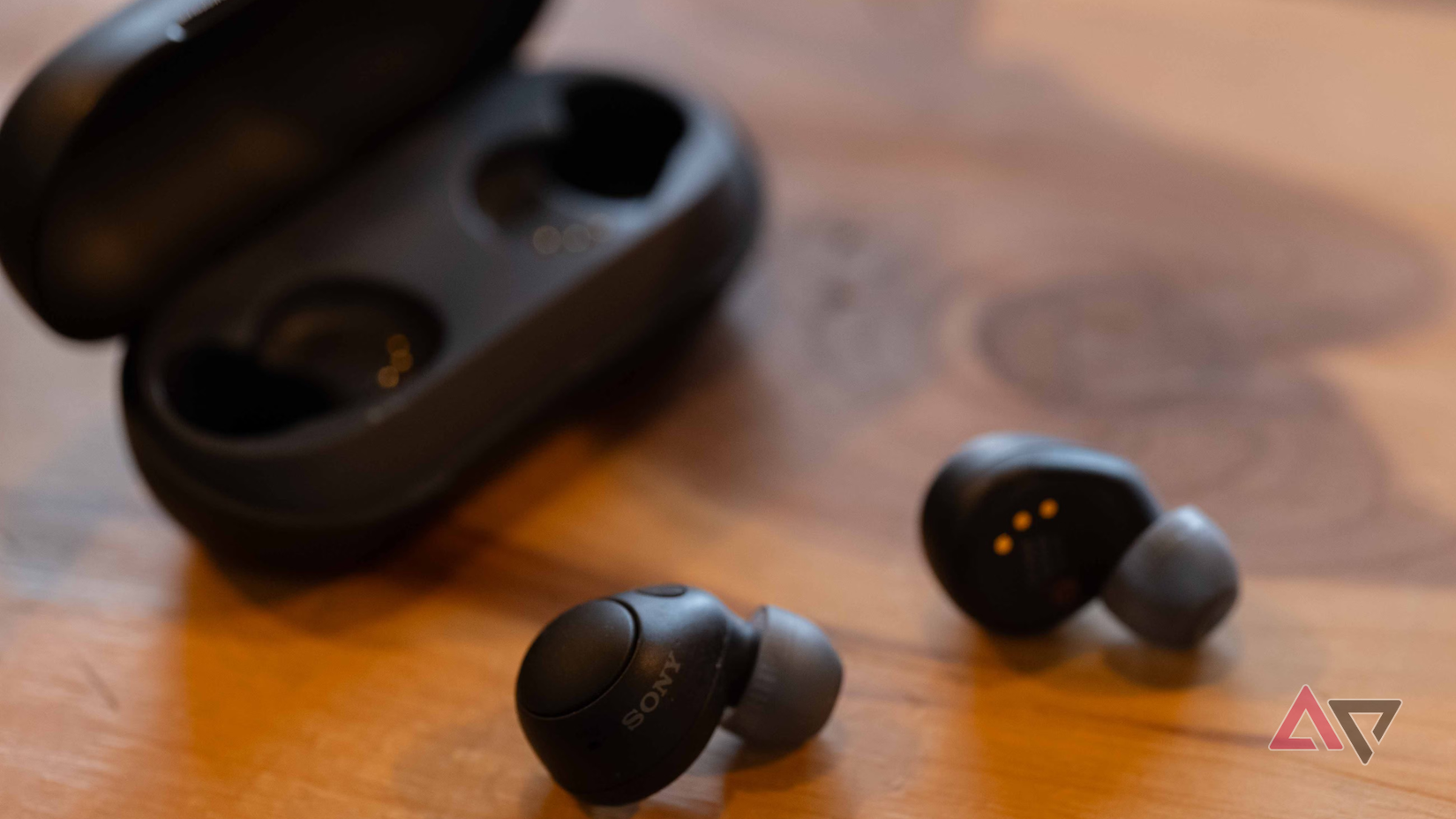 O estojo de carregamento Sony WF-C700N aberto em uma mesa de madeira