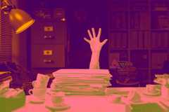A hand grasping at the air in desperation over a stack of papers as its owner sinks behind a cluttered desk