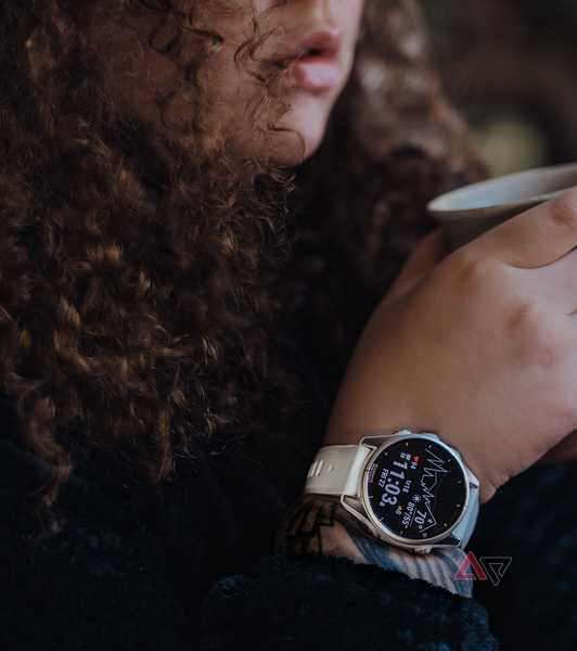 Woman wearing Garmin Fenix 8 smartwatch holding coffee mug