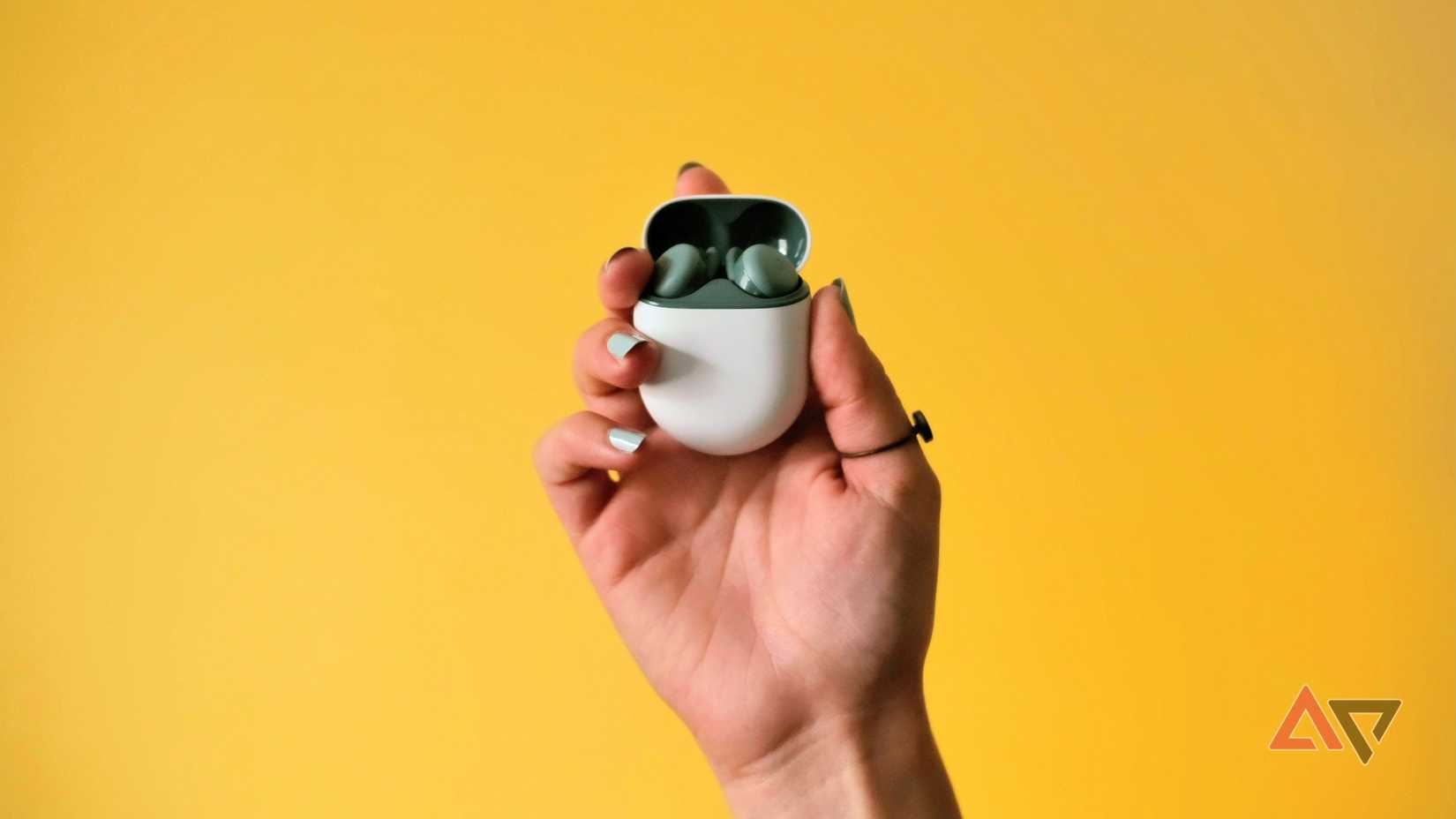 The Pixel Buds A-Series in a woman's hand in front of a yellow background.