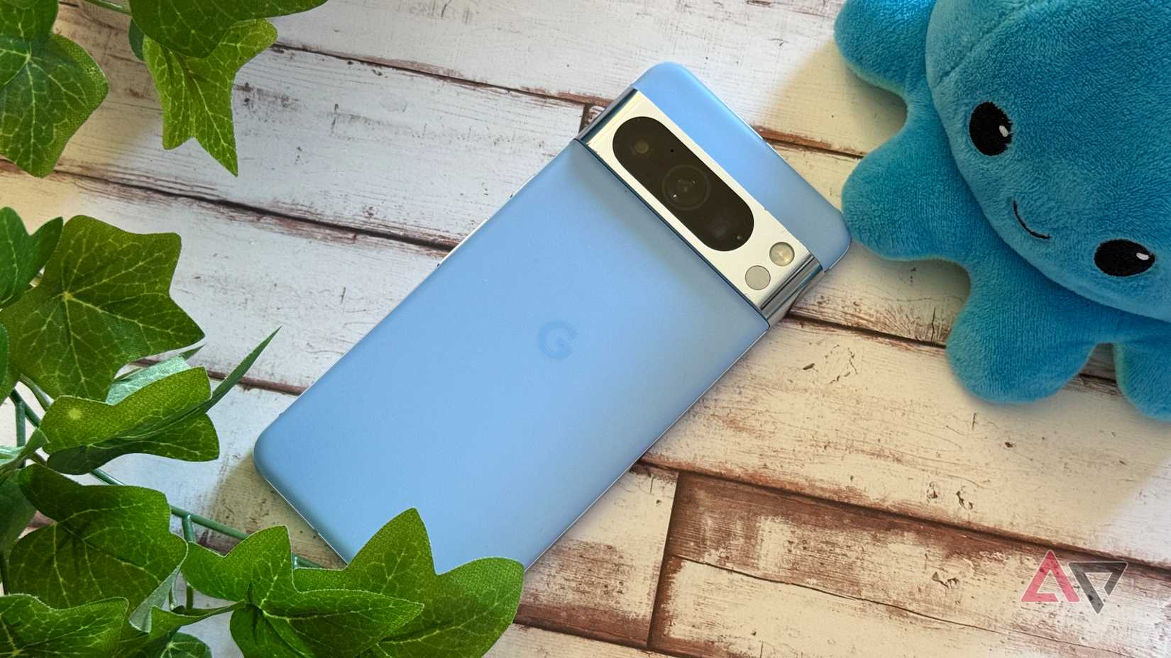 Google Pixel 8 Pro laying next to a fake plant and a plushie