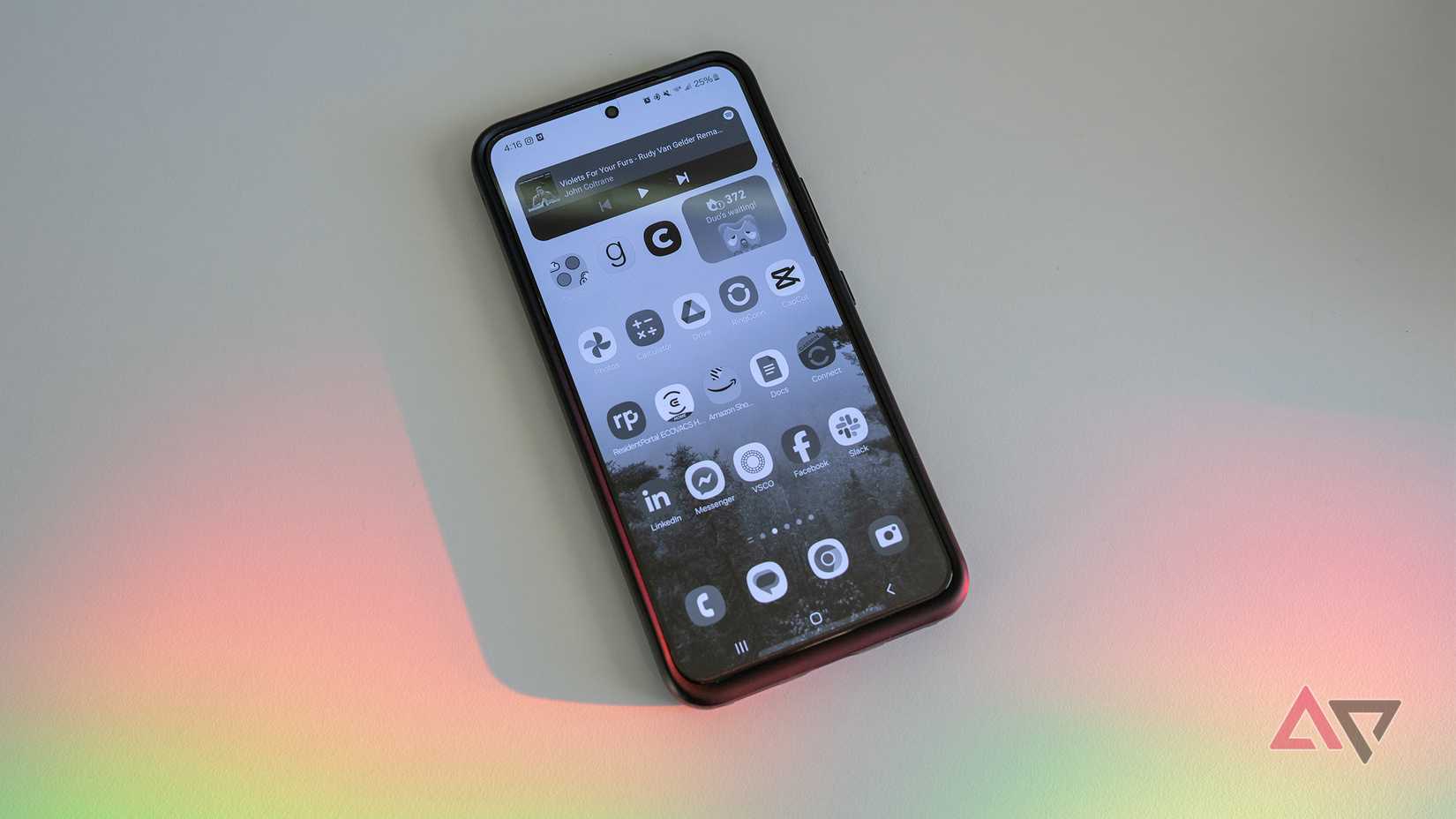 Um Samsung Galaxy com tela em preto e branco fica sobre uma mesa branca com luz de arco-íris.