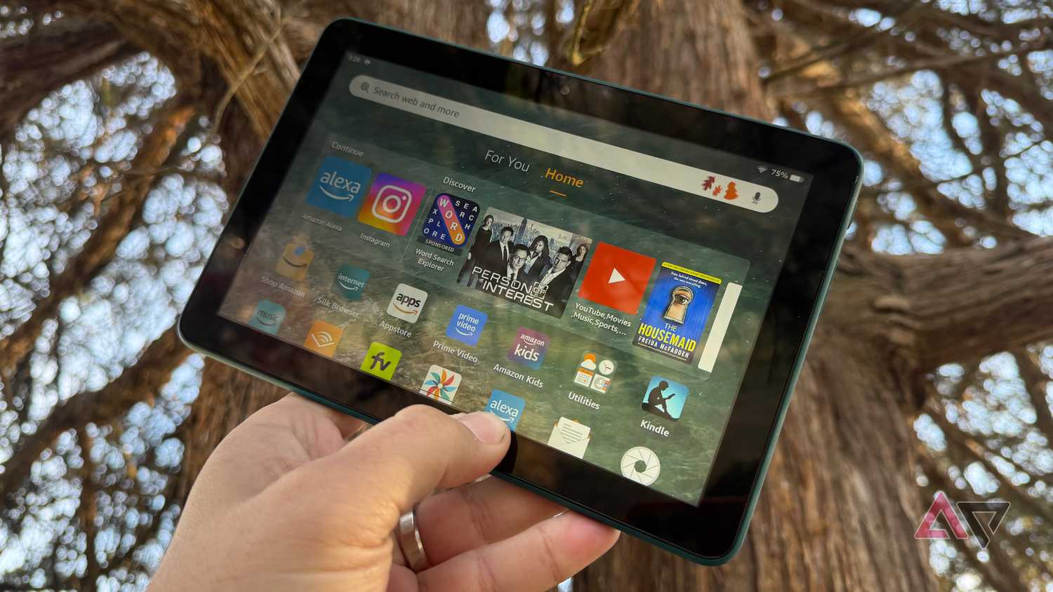 Amazon Fire HD 8's home screen displayed against an old tree at dusk