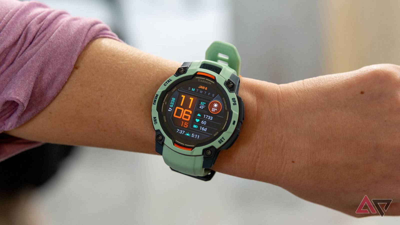 A green smartwatch reading 11:06 on a woman's wrist.