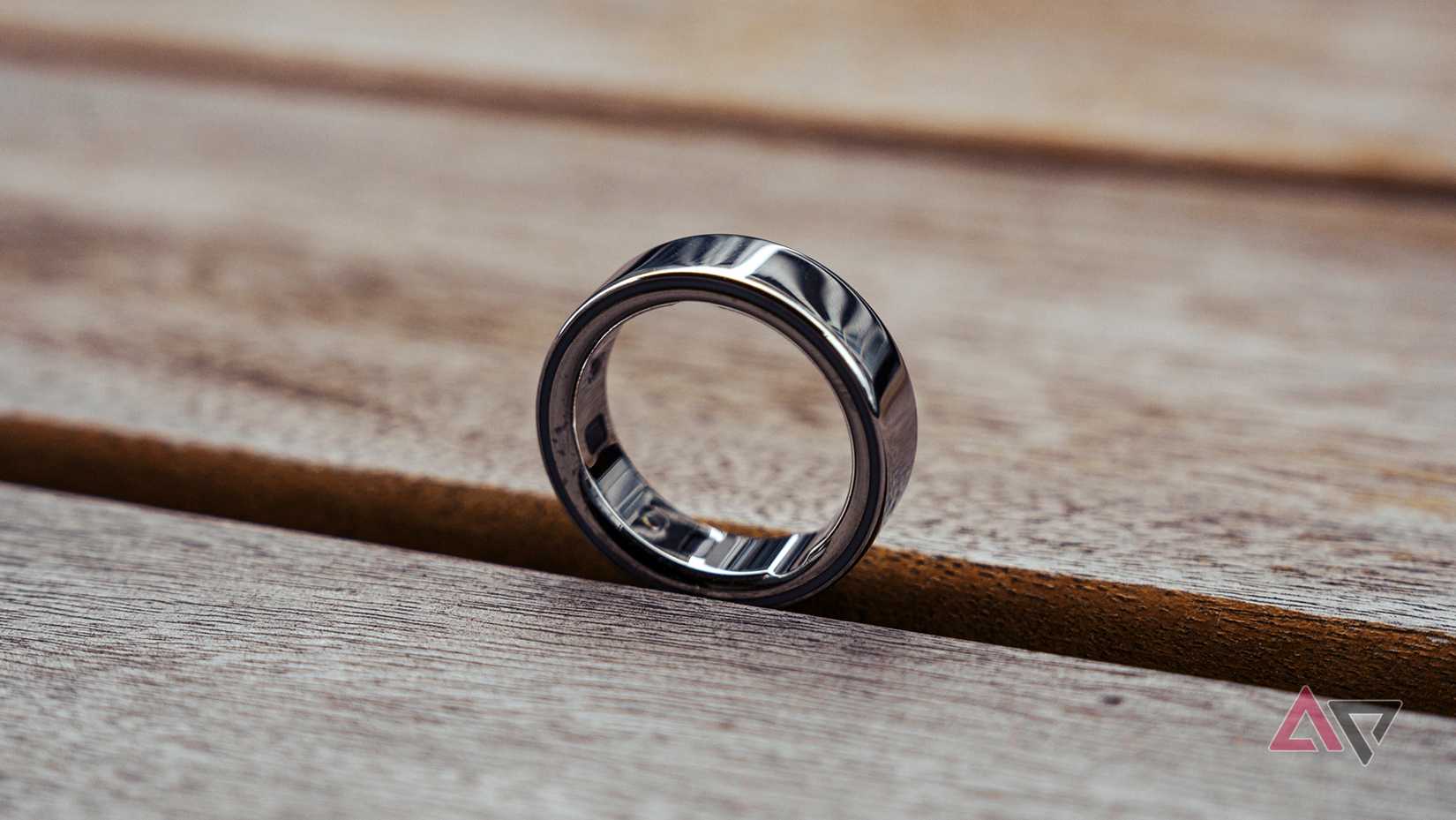 Oura Ring 4 sitting upright on its own atop a wooden table.