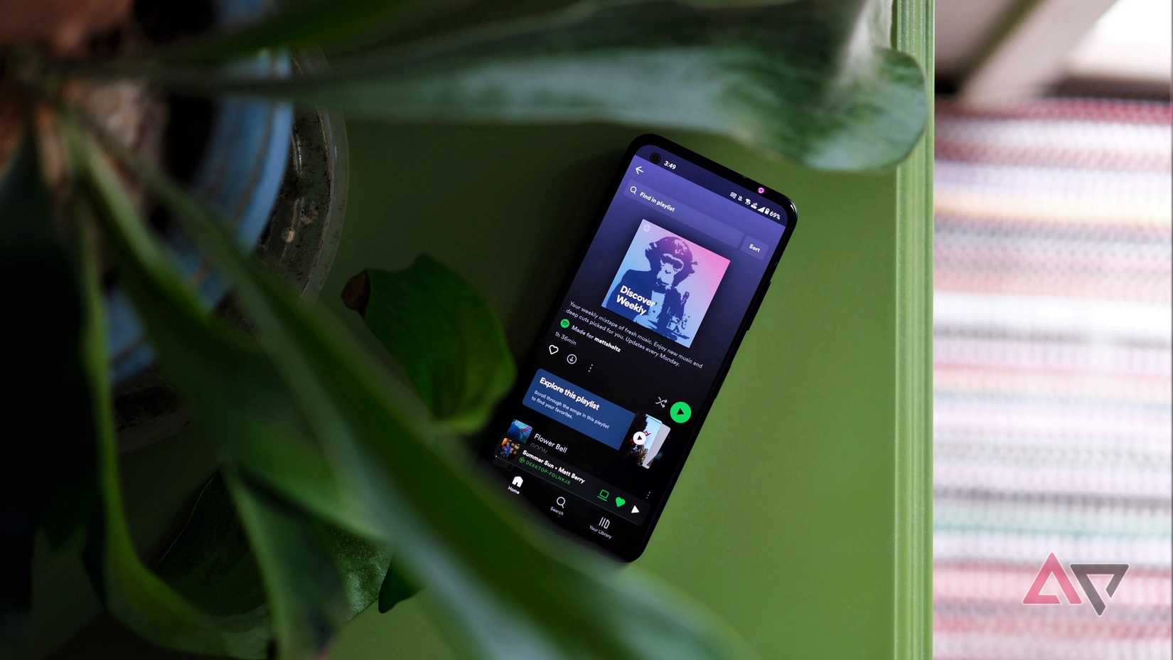 Asus Zenfone laying on green table with Spotify playing on the screen