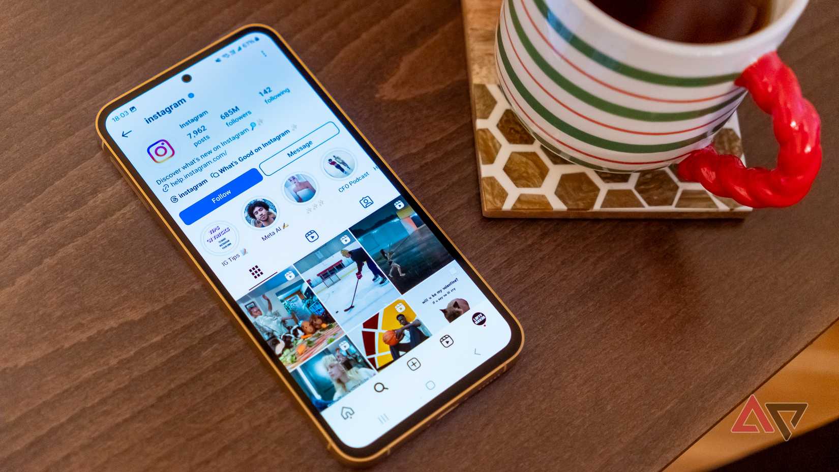 um telefone exibindo a página do instagram em uma mesa de madeira ao lado de uma xícara de chá