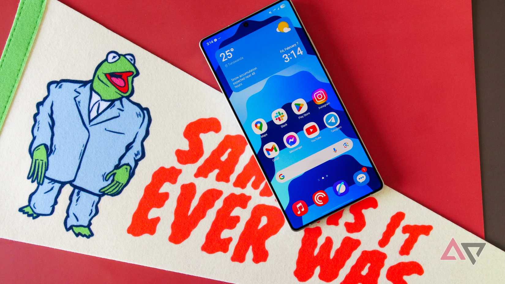 The Galaxy S25 Ultra with its home screen showing, laying on a pennant that reads 'Same as it ever was.'