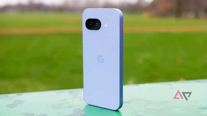 Google Pixel 9A stands up in a garden, with the purple back appearing towards the camera.