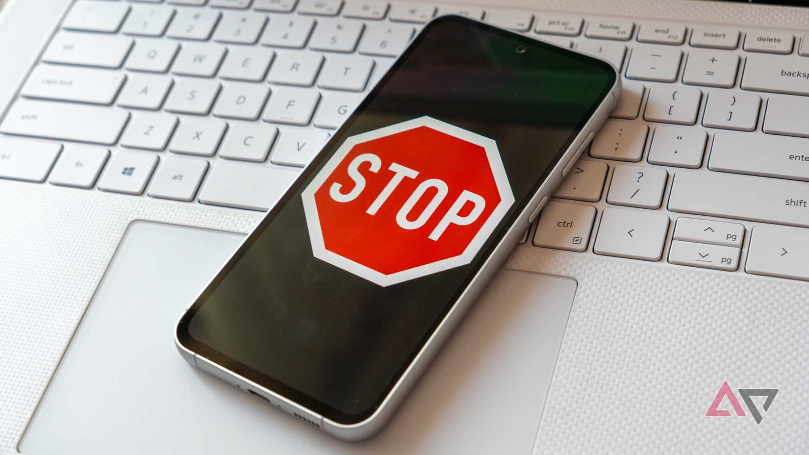 a phone displaying a stop sign on a white laptop keyboard