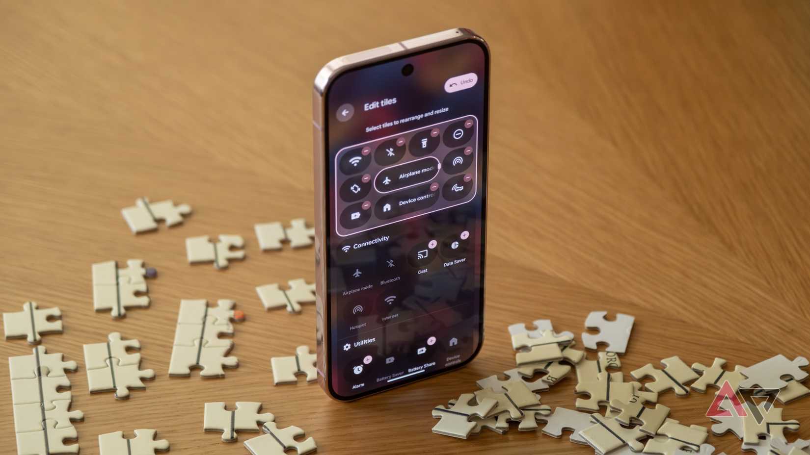 A Pixel 9 Pro open to quick settings, sitting upright among puzzle pieces.