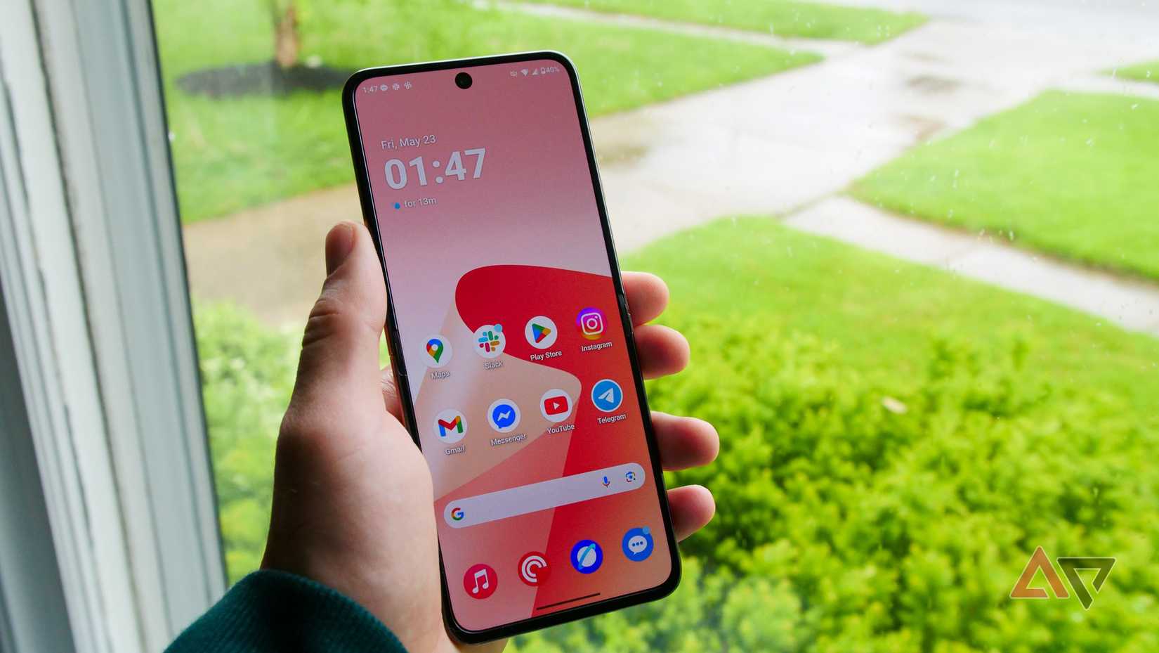 O Moto Razr Ultra segurado na mão próximo a uma janela.