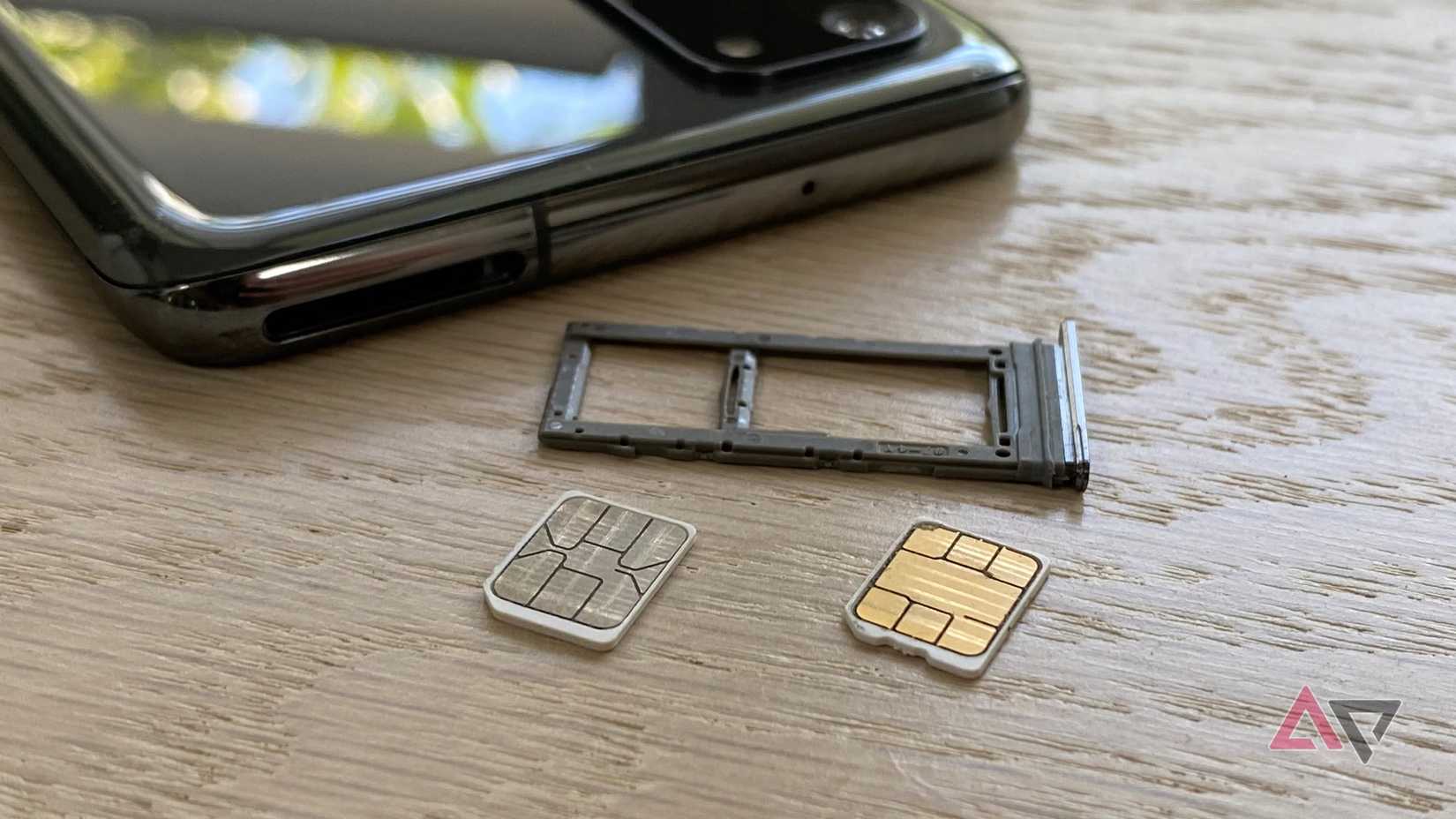 Two SIM cards sitting next to an empty SIM card tray.