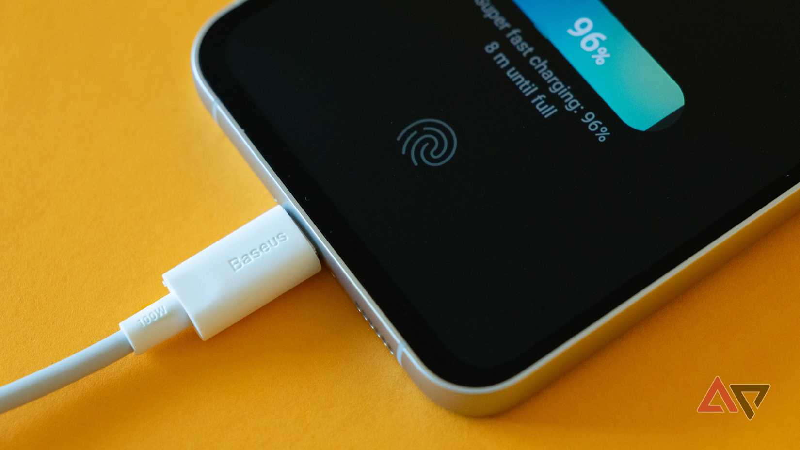 um close de um telefone carregando via cabo na superfície amarela