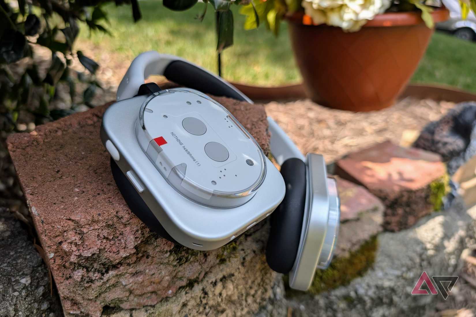 Nothing headphones (1) on a brick wall with flowers in the background