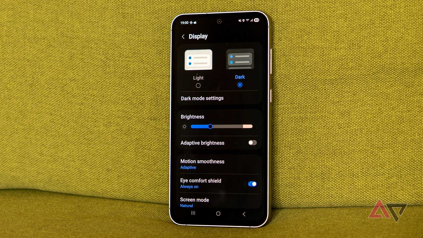 um telefone Samsung Galaxy com modo escuro ativado em um sofá verde