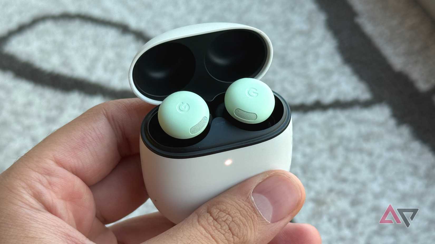 Pixel Buds Pro 2 in hand with LED charging indicator turned on