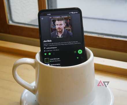 spotify on the scren of a phone that is stiting in a coffee cup