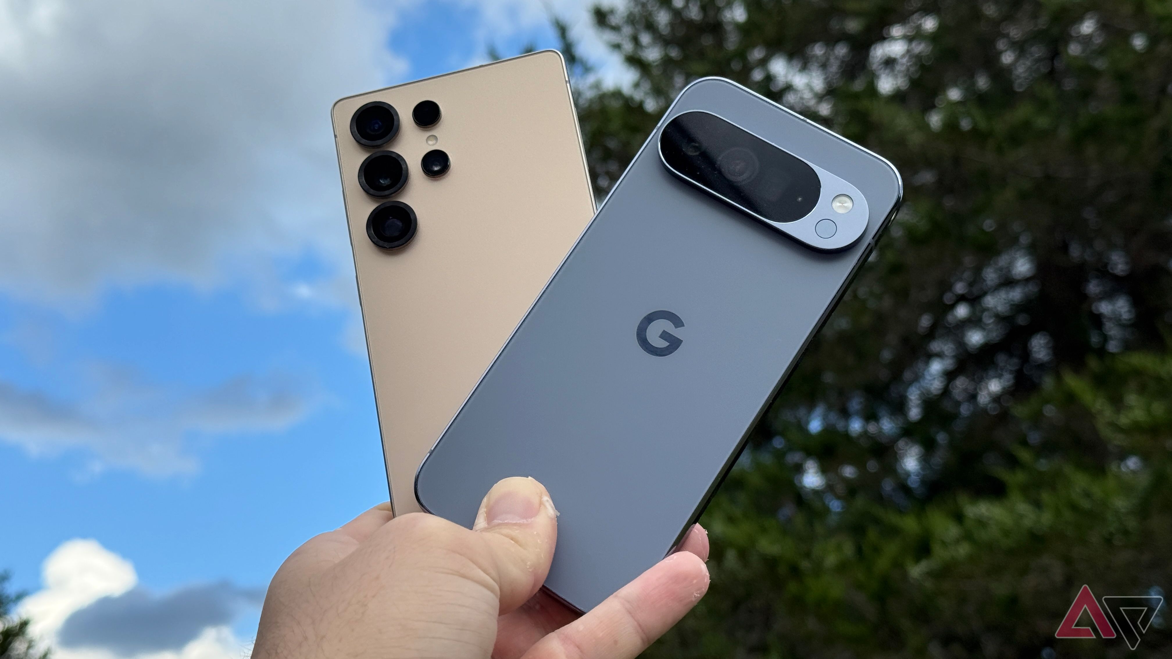 Google Pixel 10 Pro XL and Samsung Galaxy S25 Ultra held up against a blue sky