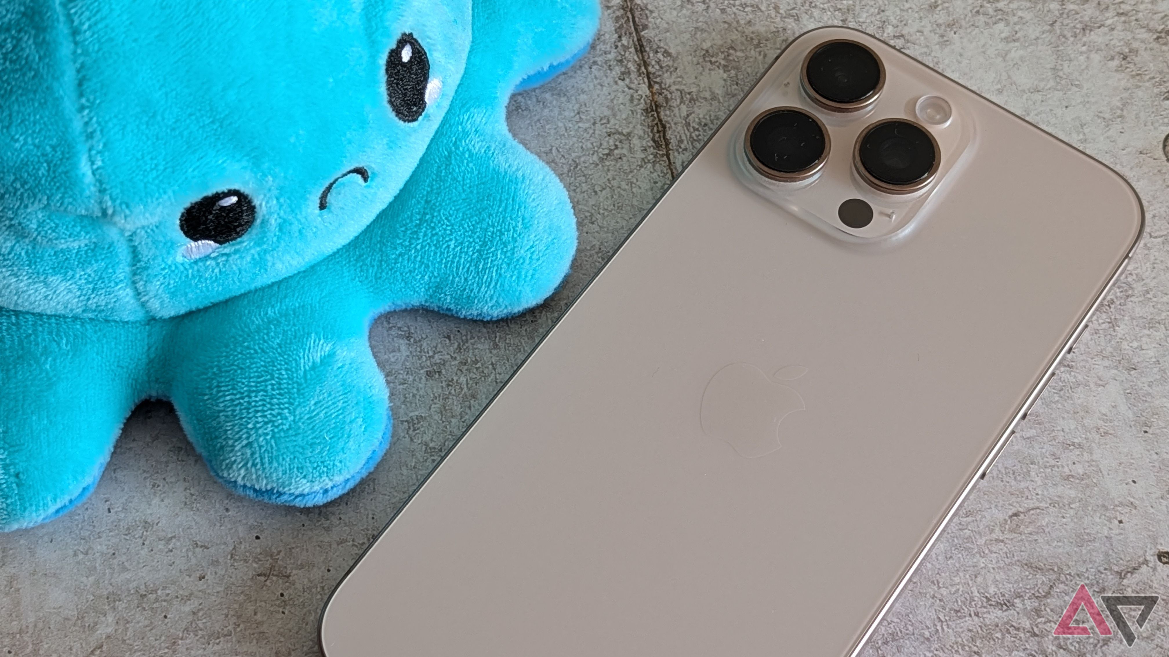 Apple iPhone 16 Pro Max next to a disgruntled plush