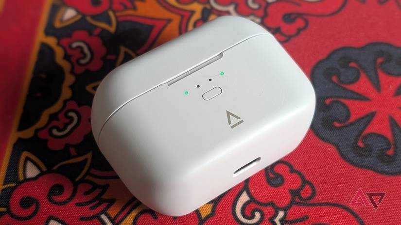 white earbuds case from creative resting on red patterned surface