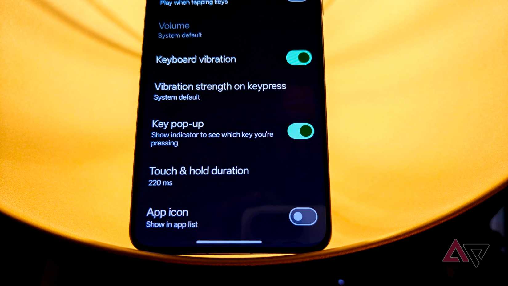 OnePlus 13 in a lamp with a warm light behind it showing the preferences page of Gboard settings.