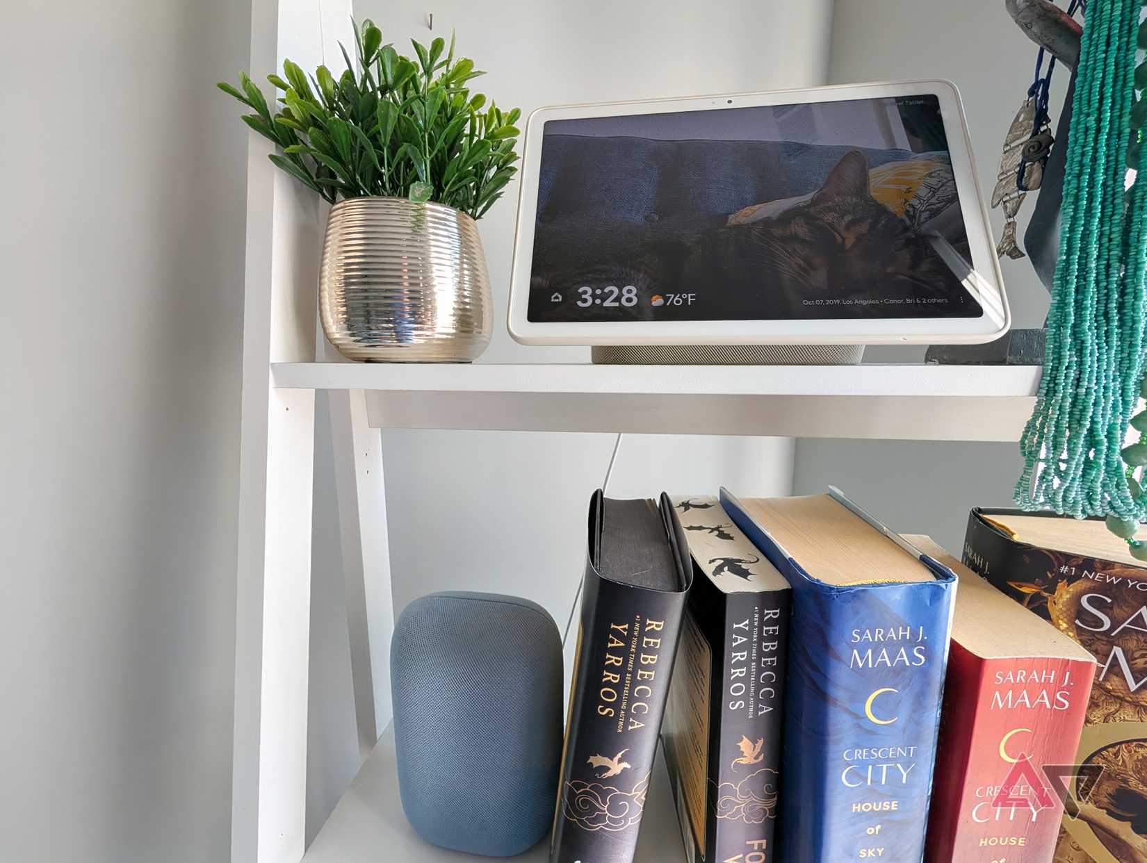 A Nest Audio and Pixel Tablet on the dock on a bookshelf.