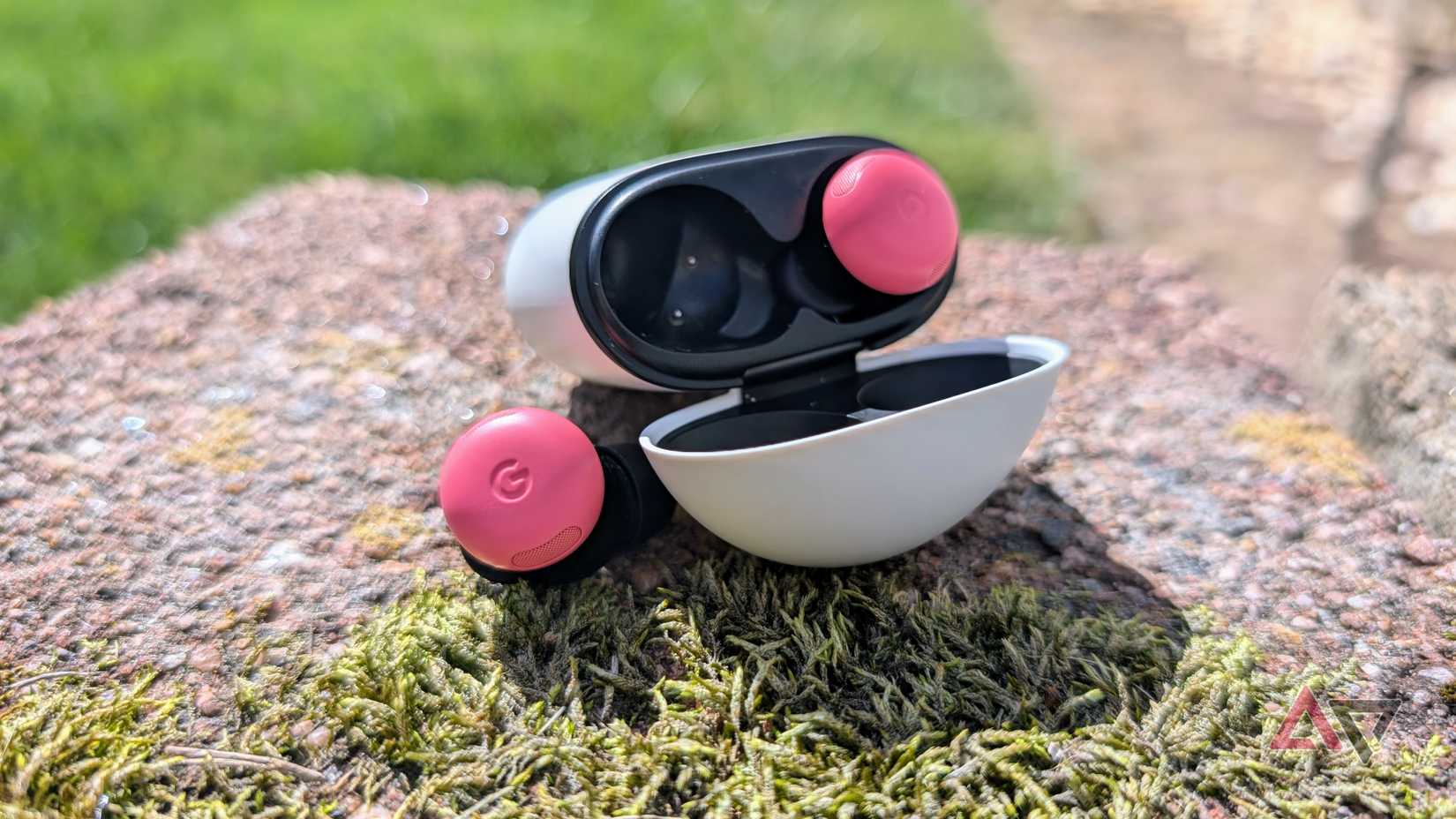 Google Pixel Buds Pro 2 case open with one bud out on a mossy rock