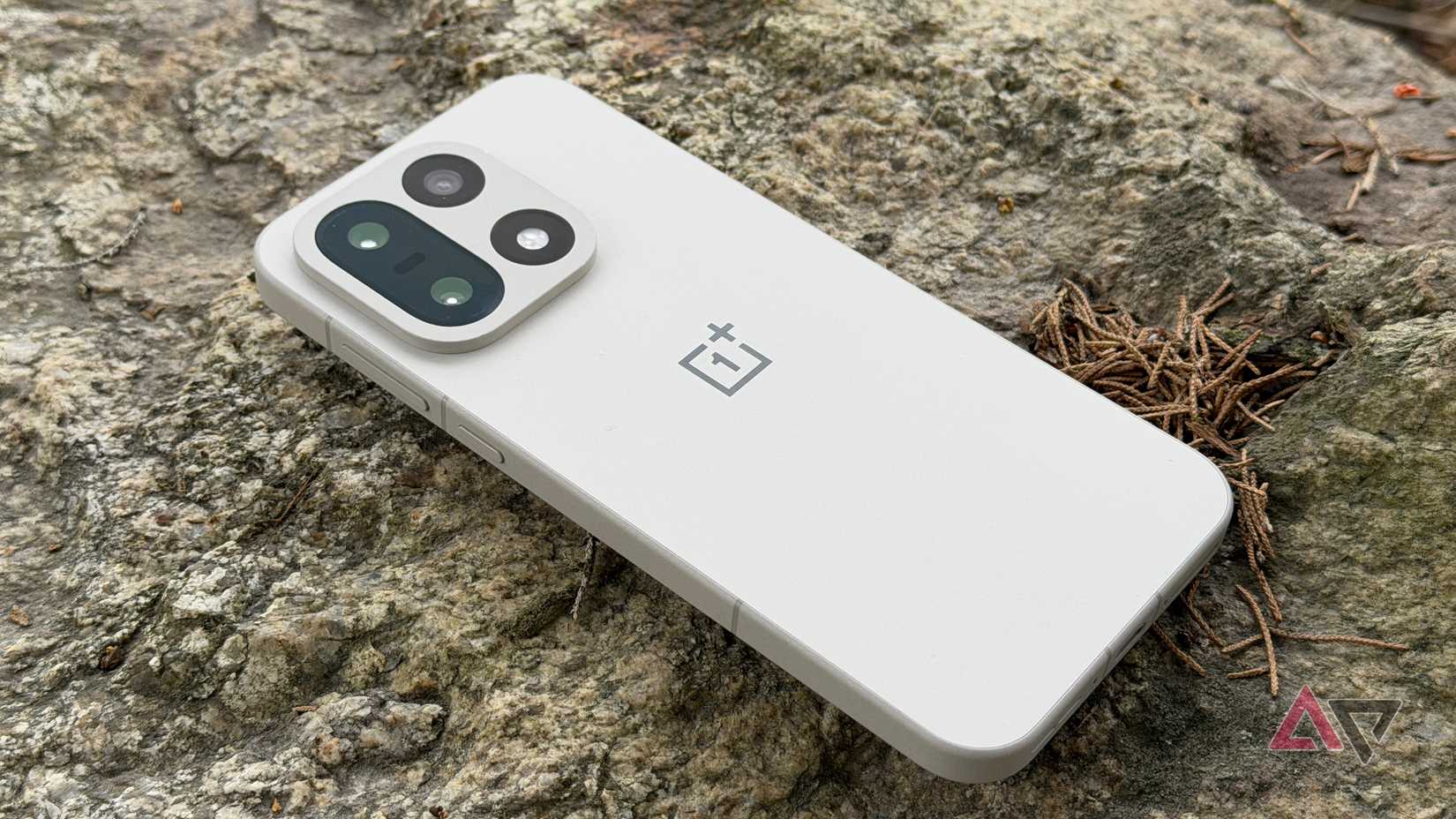 OnePlus 15 sentado de bruços contra uma pedra