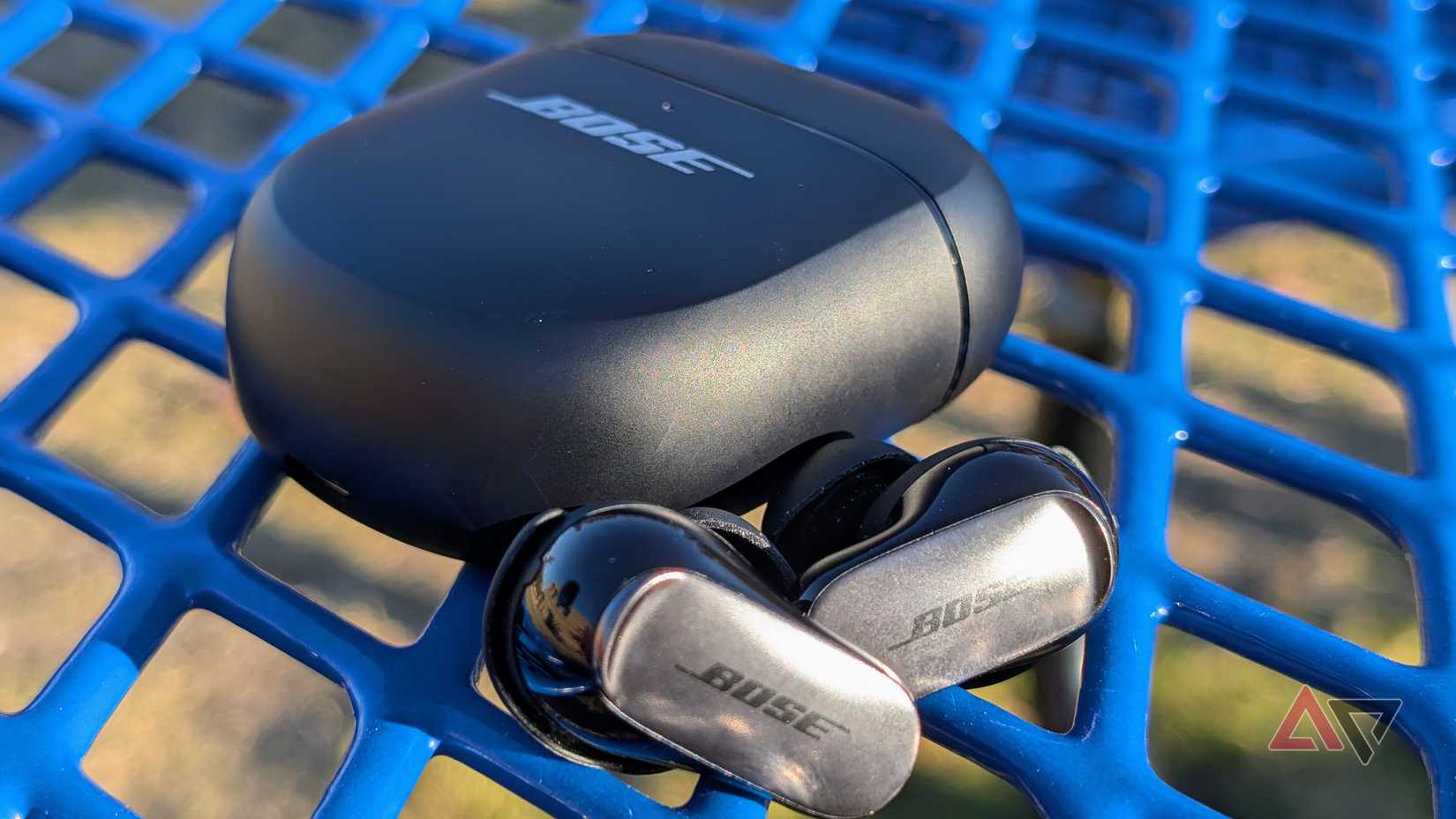 Os fones de ouvido Bose QuietComfort Ultra de 2ª geração colocados em uma mesa azul externa