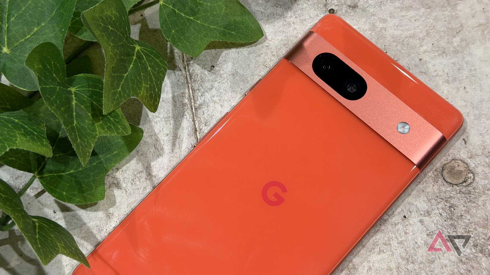 Google Pixel 7a apresentado ao lado de uma planta falsa