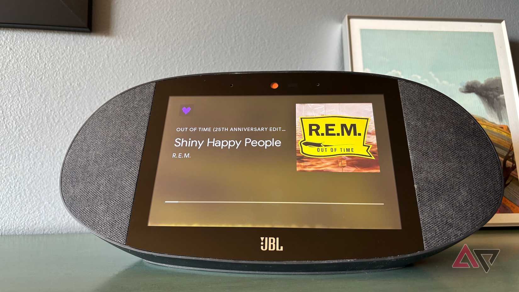 A Google Home JBL speaker playing "Shiny Happy People" by REM on Deezer.