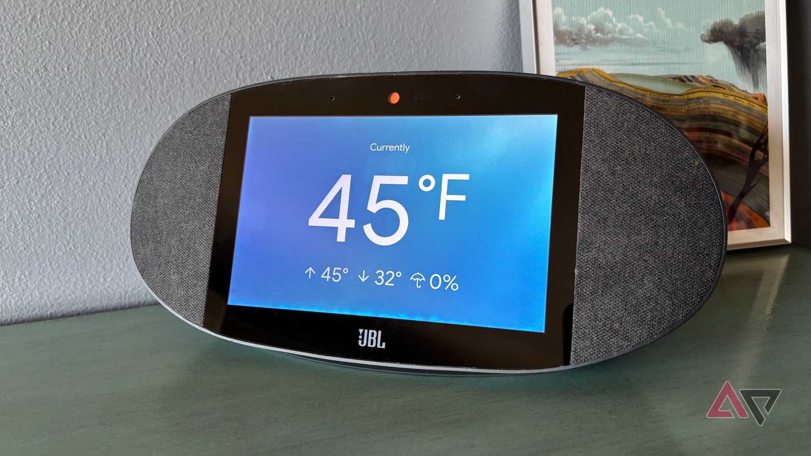 Um alto-falante JBL Google-Home exibindo a temperatura atual de 45 graus Fahrenheit, temperatura alta e baixa e possibilidade de chuva por meio do Google Weather.