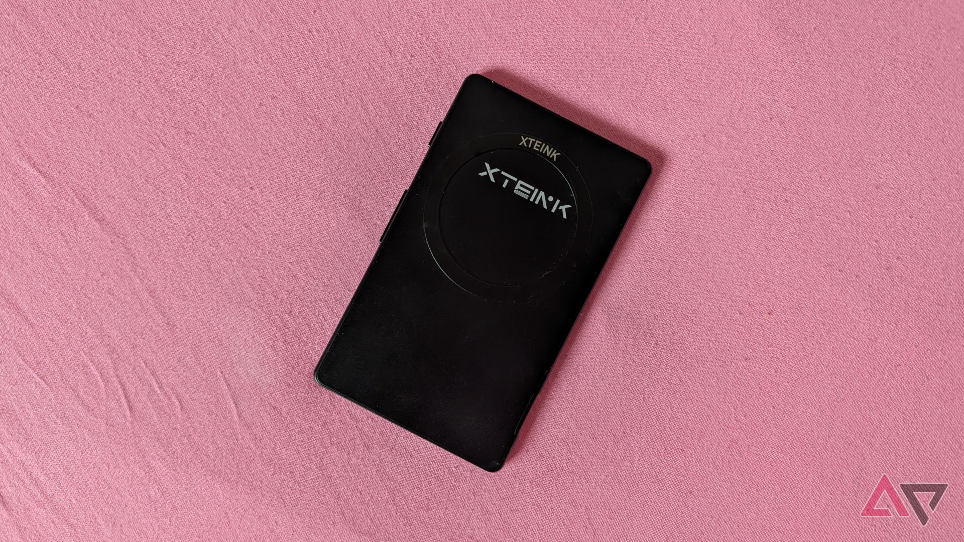 The Xteink X4 laid on a pink bedsheet.