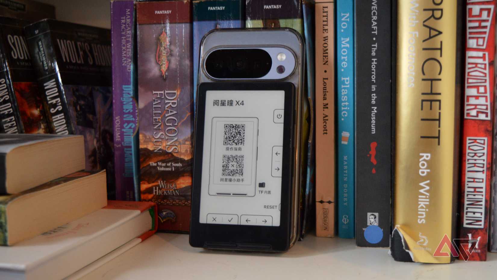 O Xteink X4 na parte traseira de um Pixel 10 Pro, apoiado em uma estante.