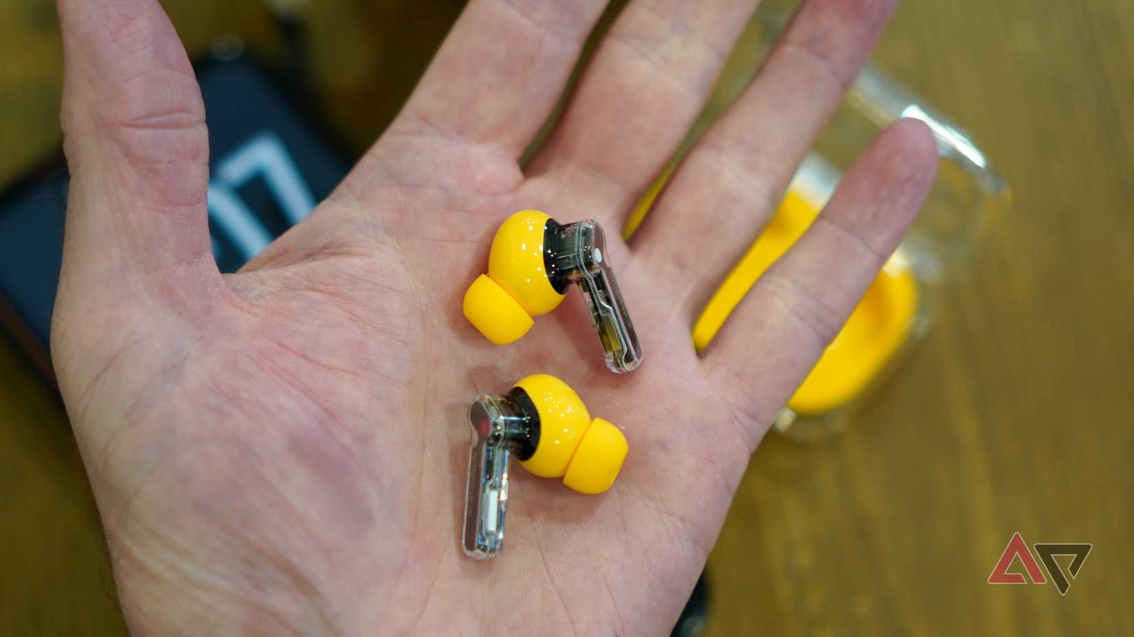 Una persona che tiene in mano gli auricolari Nothing Ear (a).