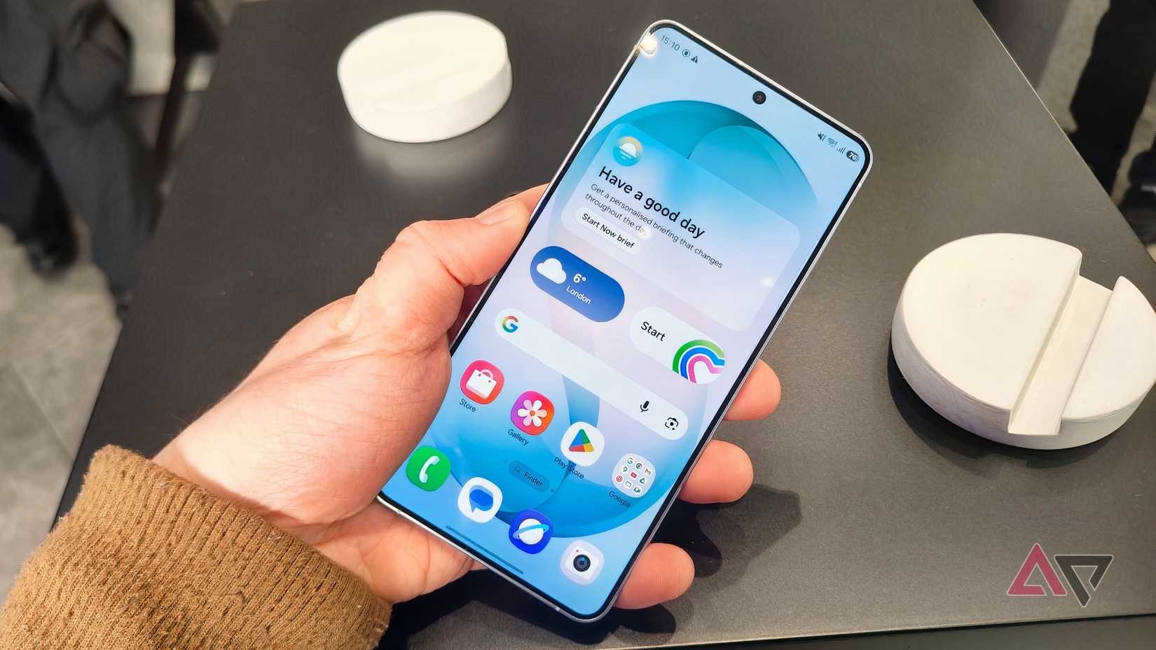 O Samsung Galaxy S26 Plus em sua tela inicial, com a mão de um homem segurando-o em um ângulo inclinado.