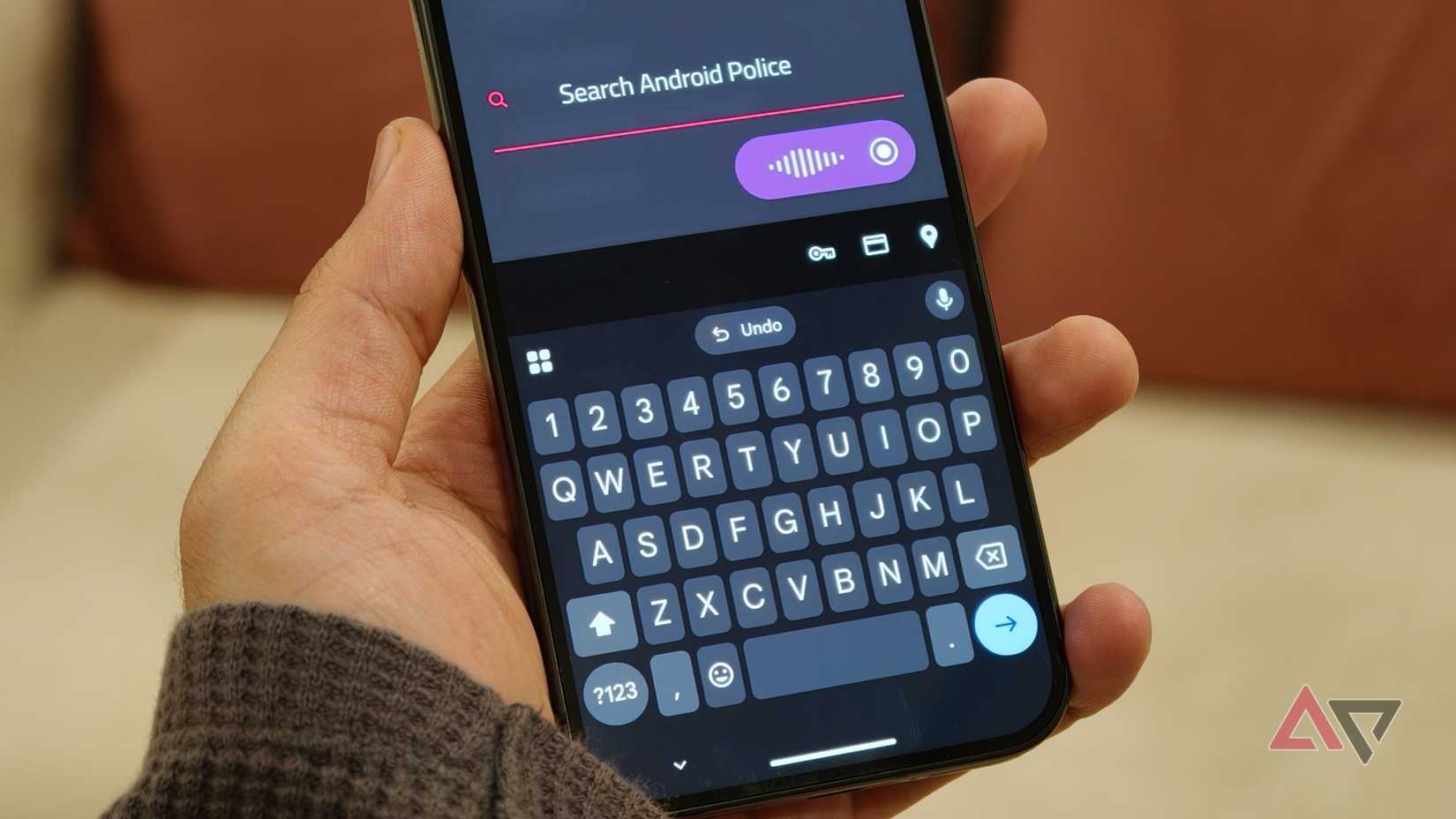 Mão segurando o telefone enquanto pesquisa no Android Police usando digitação por voz
