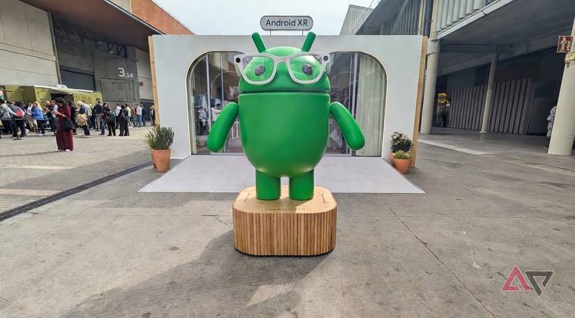 A photo of the Android Bugdroid wearing glasses in front of an Android XR booth