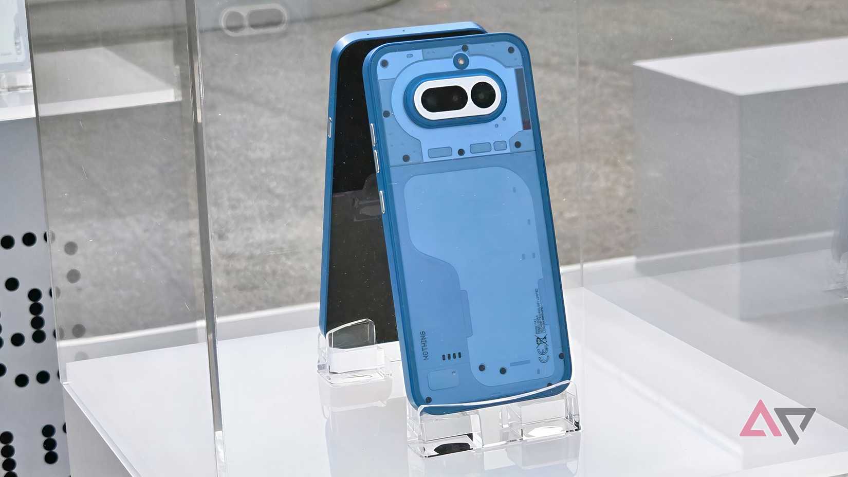 O modelo azul do Nothing Phone (4a) atrás de uma caixa de vidro.