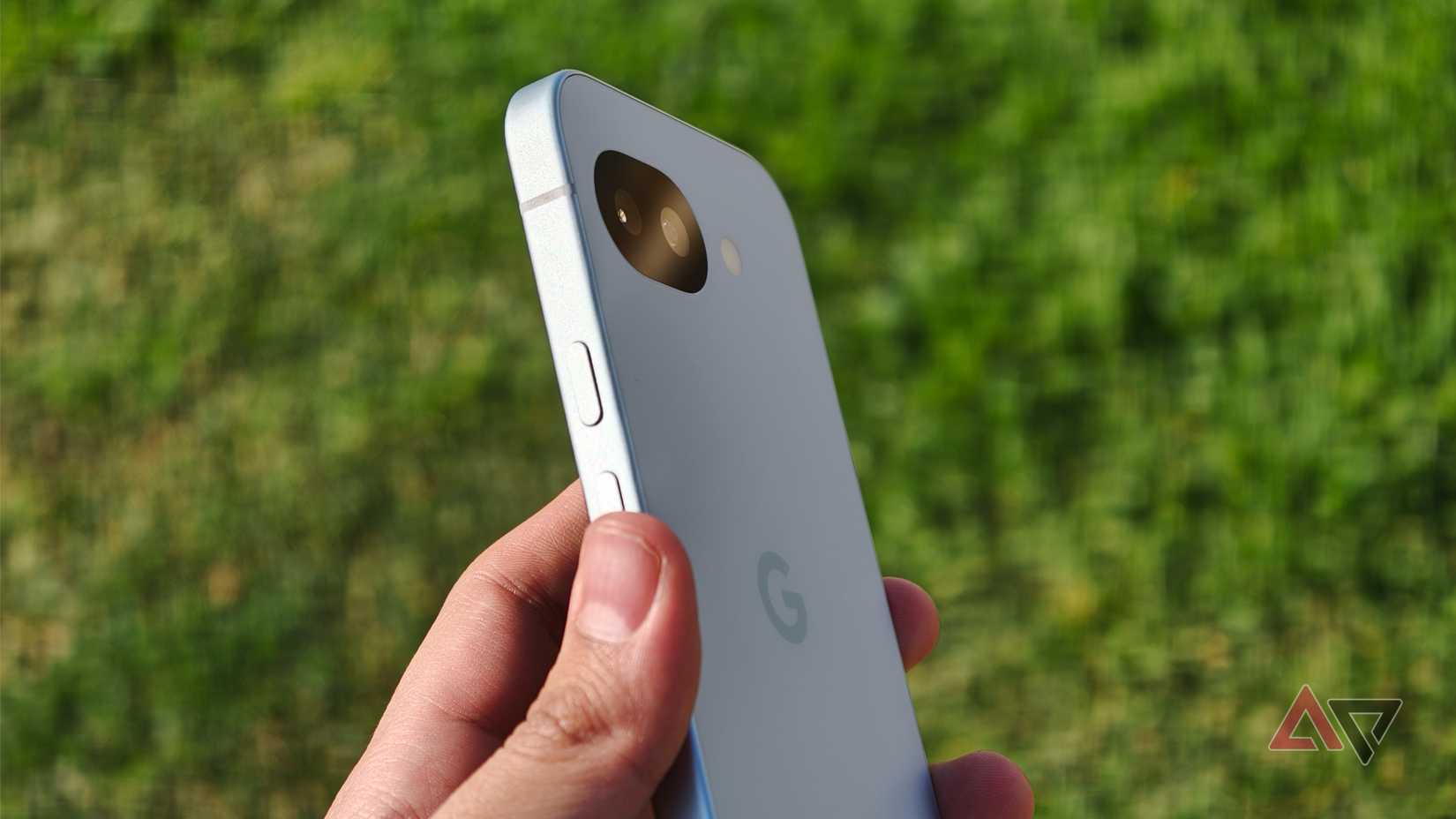 Google Pixel 10a in hand in front of green grass