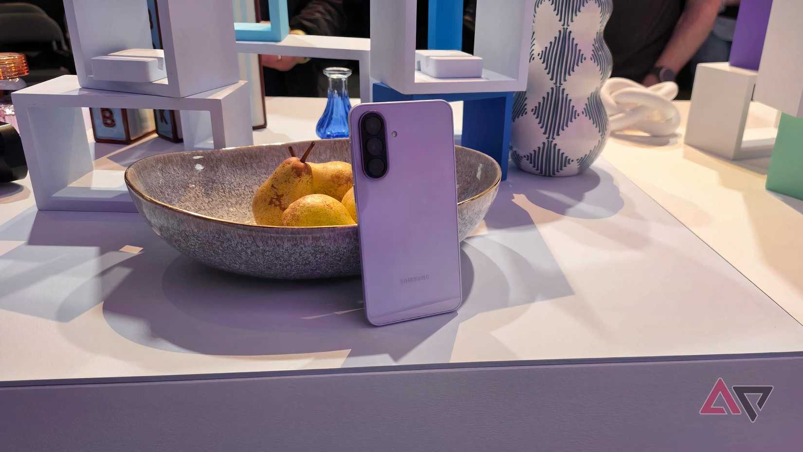 O Samsung Galaxy A37 lilás apoiado em uma tigela de pares.